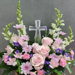 Pink and white floral arrangement with a silver cross centerpiece