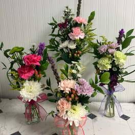 Three mixed flower bouquets in glass vases with ribbon bows