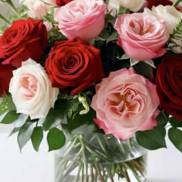 Bouquet of red, pink, and white roses in a clear glass vase