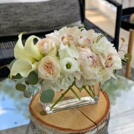 White and blush floral arrangement in a clear square vase