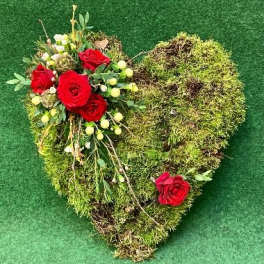 Heart-shaped moss arrangement with red roses and small white flowers