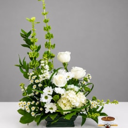 White roses and daisies arranged in a low green container with tall green spikes