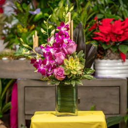 Pink orchids and roses arranged in a glass vase with a succulent accent