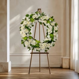 White floral wreath on a wooden easel in a bright room