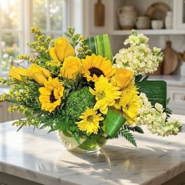 Yellow roses and sunflowers in a glass vase with white flowers