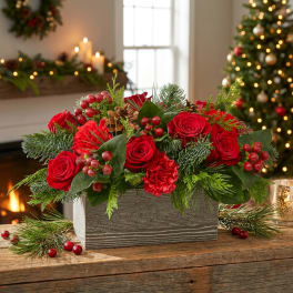 Red roses and carnations in a gray wooden box with evergreen accents
