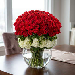 Red roses and white hydrangeas arranged in a clear glass bowl vase