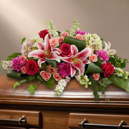 Pink and white floral arrangement on a casket with roses and lilies
