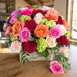 Mixed roses in a rustic wooden box with a candle nearby