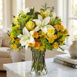 Yellow roses and white lilies in a clear glass vase