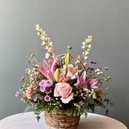 Pink lilies and roses arranged in a wicker basket