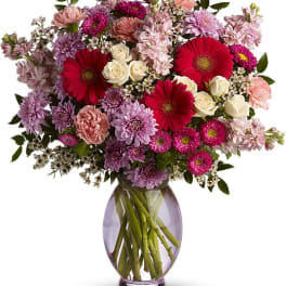 Mixed pink and purple bouquet with red gerbera daisies in a glass vase