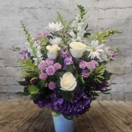 Mixed bouquet in a blue vase with white roses, purple hydrangea, and daisies