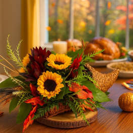 Cornucopia centerpiece with yellow sunflowers and dark red blooms on a wooden slice base