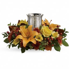 Autumn floral centerpiece with yellow lilies and roses around a silver vase