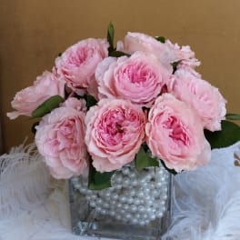 Pink roses in a square glass vase filled with white pearls