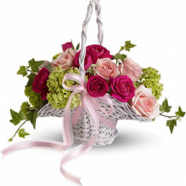 Pink and blush roses in a white wicker basket with a ribbon handle
