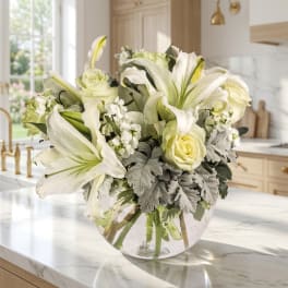 White lilies and pale roses in a clear glass vase