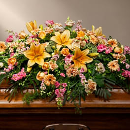 Large casket spray with yellow lilies, pink roses, and peach daisies