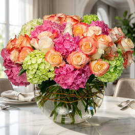 Pink and peach roses with hydrangeas in a clear glass vase