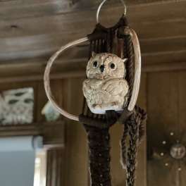 Ceramic owl ornament hanging from a woven macrame ring