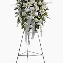 White floral standing spray on an easel with ribbon streamers
