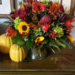 Autumn bouquet with sunflowers, roses, calla lilies, and berries in a glass vase
