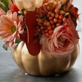 Pink and peach flowers arranged in a gold pumpkin-shaped vase