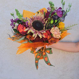 Mixed bouquet with a large sunflower and orange-purple blooms wrapped in orange paper
