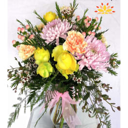 Mixed pastel bouquet in a glass vase with pink and yellow blooms
