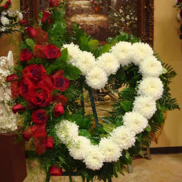 Heart-shaped floral wreath with white and red flowers on an easel