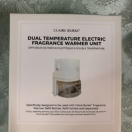 Boxed Claire Burke electric fragrance warmer unit on patterned fabric