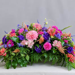 Low floral centerpiece with pink, purple, and coral blooms