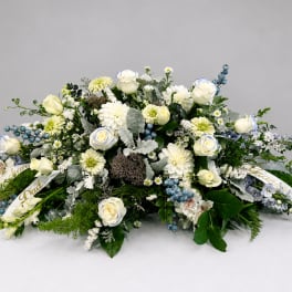 Large white floral arrangement with blue accents and ribbon