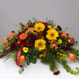Large floral spray with sunflowers, orange roses, and burgundy blooms
