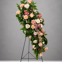 Tall floral spray with peach and white roses on a black stand