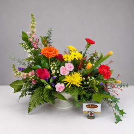 Colorful mixed flower arrangement in a white pedestal vase