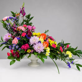 Colorful mixed flower arrangement in a white pedestal vase