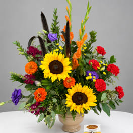Bright mixed bouquet with sunflowers, orange and red blooms in a beige vase