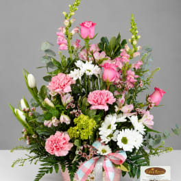 Pink and white mixed flower arrangement in a decorated basket with ribbon