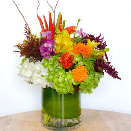 Colorful mixed flower arrangement in a green glass vase