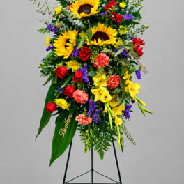 Tall standing floral spray with sunflowers, roses, and carnations on an easel