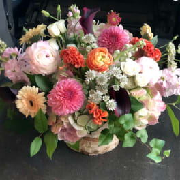 Mixed bouquet in a birch container with pink, white, orange, and purple flowers