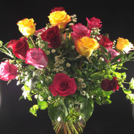 Mixed roses in a clear glass vase with small white filler flowers
