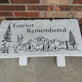 Stone memorial plaque with a deer and mountain scene and the words Forever Remembered