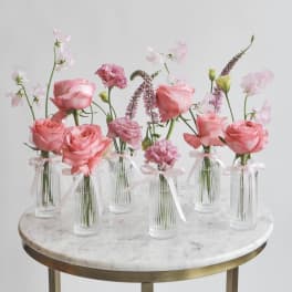 Pink roses and carnations in small glass vases with ribbon ties