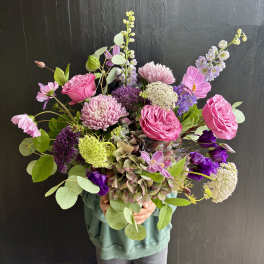 Handheld bouquet of pink and purple flowers with airy greenery