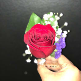 Single red rose with white baby's breath and purple filler held in hand