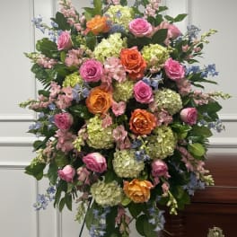 Large standing floral spray with pink, orange, and blue flowers