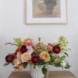 Mixed floral arrangement in a white vase on a wooden table